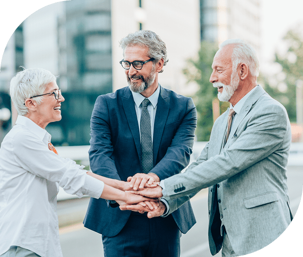 Three people smiling and shaking hands outdoors.
