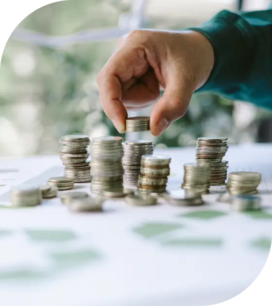 Hand stacking coins on a table.